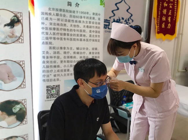 图为护理人员进行耳穴贴压治疗